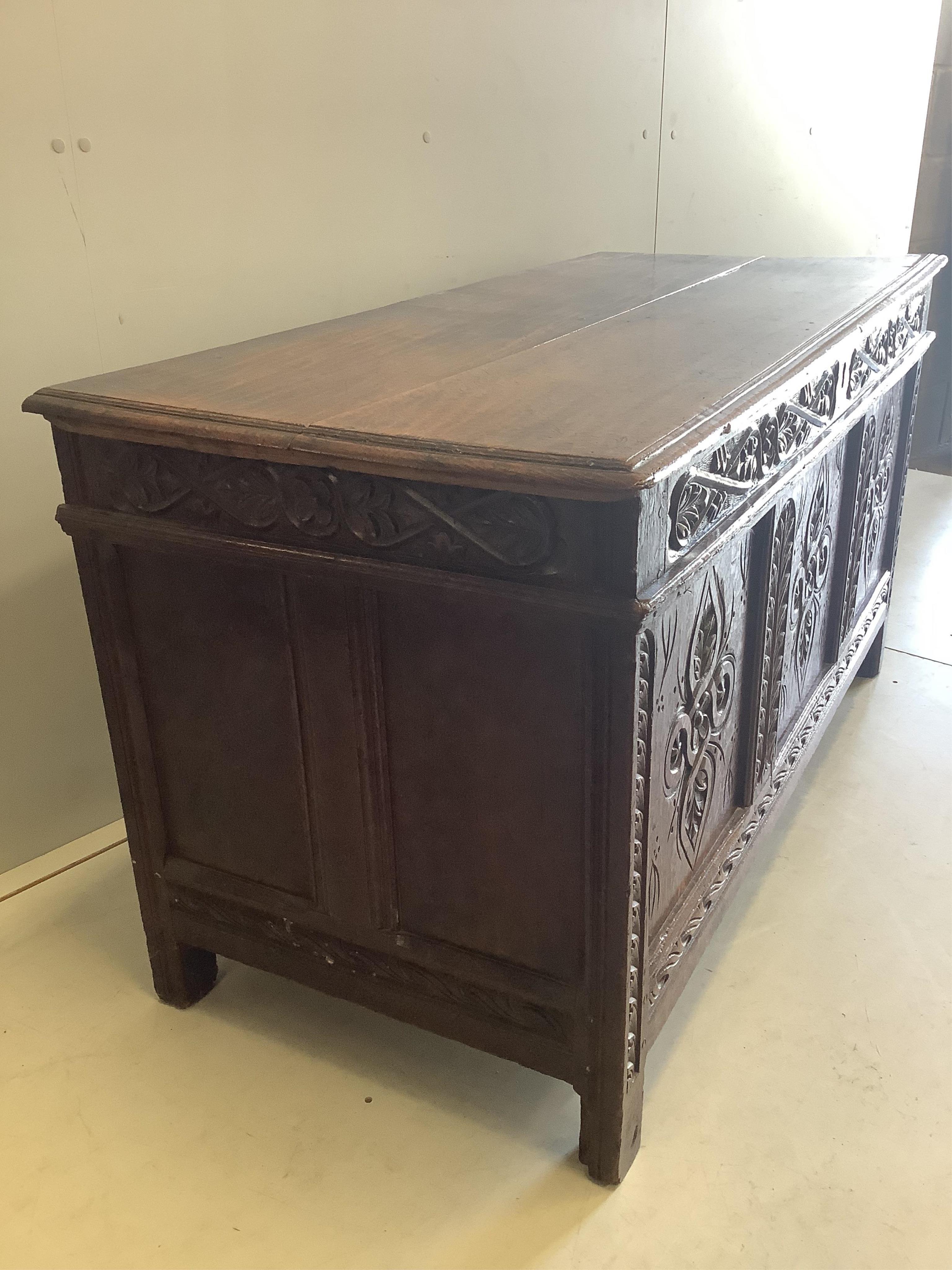 An early 18th century carved oak coffer with two plank top, width 133cm, depth 59cm, height 70cm